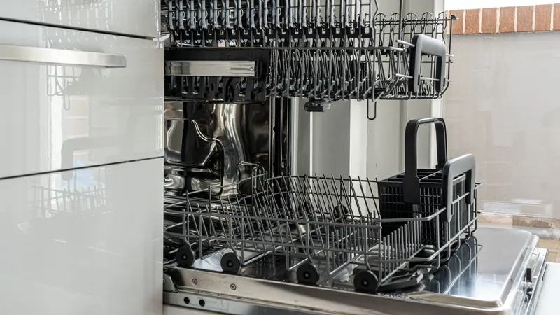 Open and empty dishwasher in a sunlit modern kitchen ready for use.