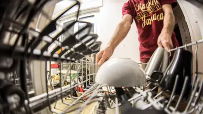 POV perspective of an adult loading dishes into a dishwasher in a home kitchen.