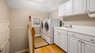 Spacious and clean laundry room featuring modern appliances and white cabinetry.