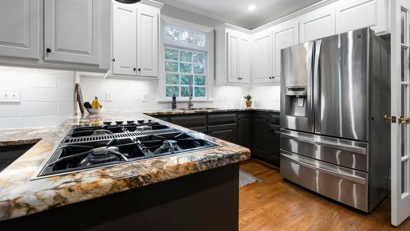 Bright modern kitchen with stainless steel fridge and elegant countertops.