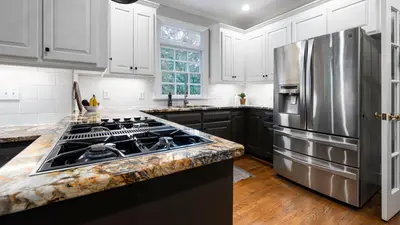 Bright modern kitchen with stainless steel fridge and elegant countertops.