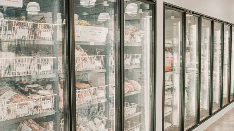Frozen meats in a retail freezer with transparent doors and organized sections.