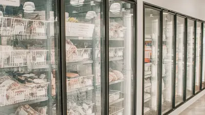 Frozen meats in a retail freezer with transparent doors and organized sections.