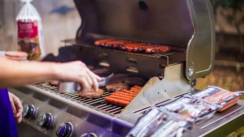 A backyard barbecue grilling sausages & burgers on a sunny day.