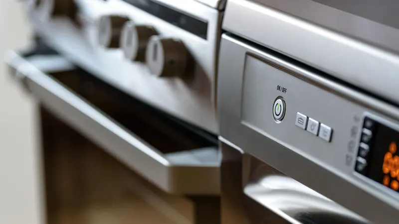 Close-up view of modern stainless steel kitchen appliances with focus on dishwasher and oven.