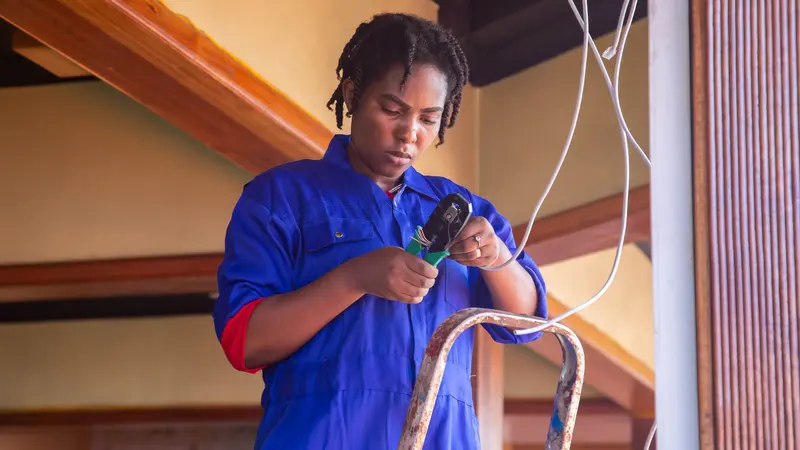 Professional electrician working on wiring in an indoor setting, demonstrating skill and concentration.