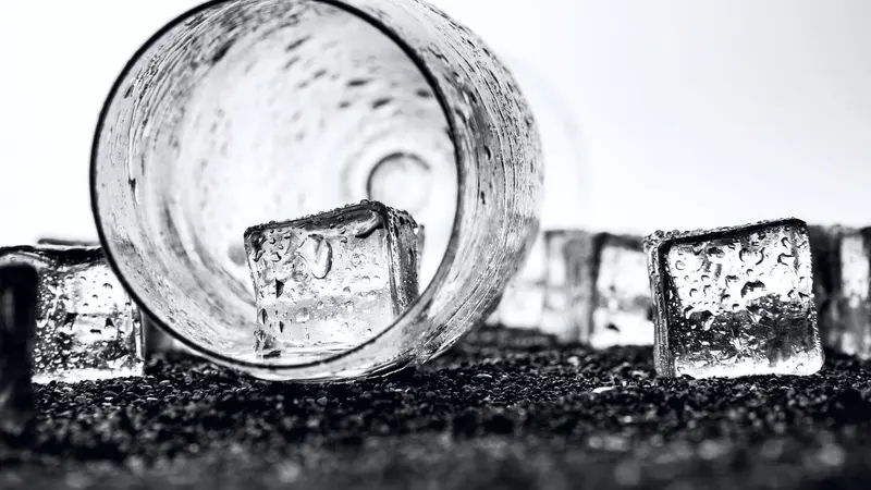 Monochrome image of ice cubes and a glass, creating a dramatic, cool atmosphere.