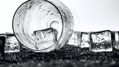 Monochrome image of ice cubes and a glass, creating a dramatic, cool atmosphere.
