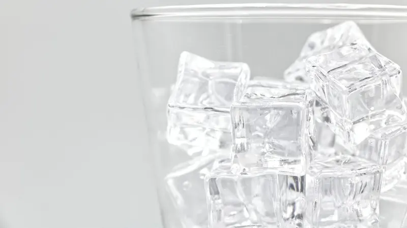 Refreshing close-up of ice cubes in a clear glass. Ideal for beverage and freshness themes.