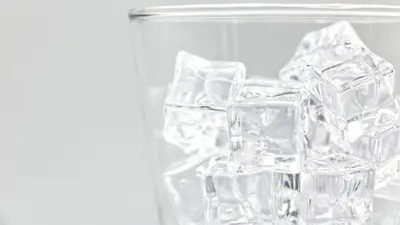 Refreshing close-up of ice cubes in a clear glass. Ideal for beverage and freshness themes.