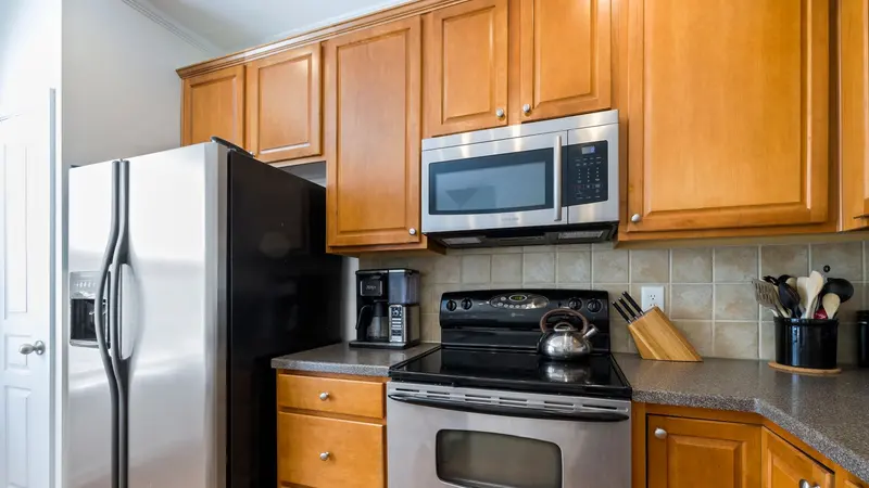 Contemporary kitchen featuring stainless steel appliances, wooden cabinets, and tile backsplash.