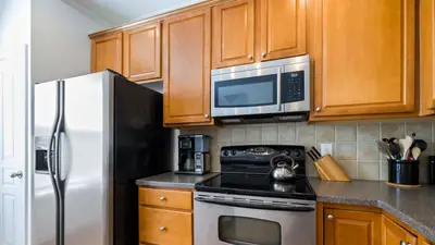 Contemporary kitchen featuring stainless steel appliances, wooden cabinets, and tile backsplash.