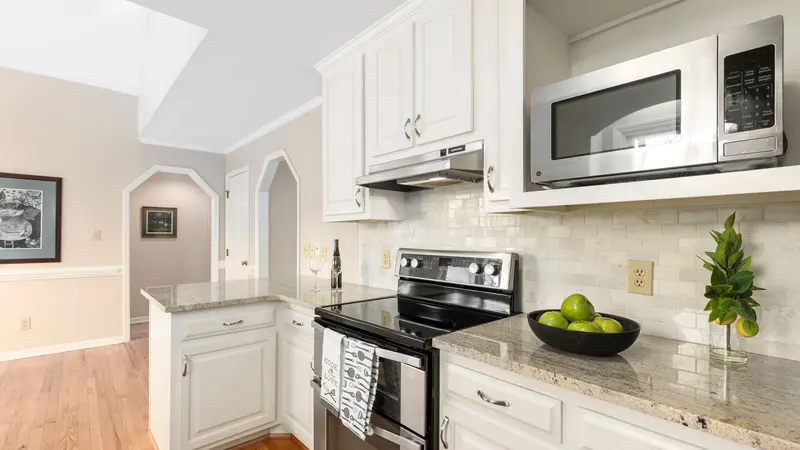 Bright and spacious kitchen featuring white cabinets, granite countertops, and stainless steel appliances.