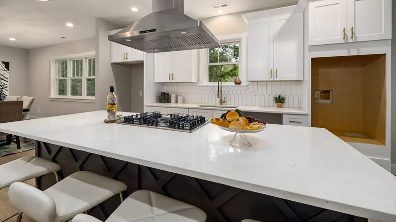 Sleek modern kitchen with white cabinets, island, and stainless range hood for a contemporary look.