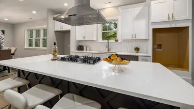 Sleek modern kitchen with white cabinets, island, and stainless range hood for a contemporary look.