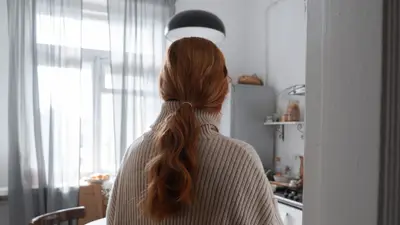 Woman with red hair stands in a cozy, well-lit kitchen surrounded by natural light and modern decor.