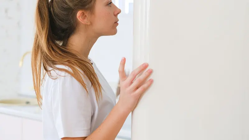 Woman looking into a white fridge in a modern domestic kitchen setting.