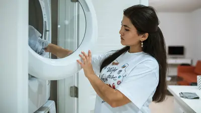 A woman loads clothes into a modern washing machine, focusing on laundry in a stylish home setting.